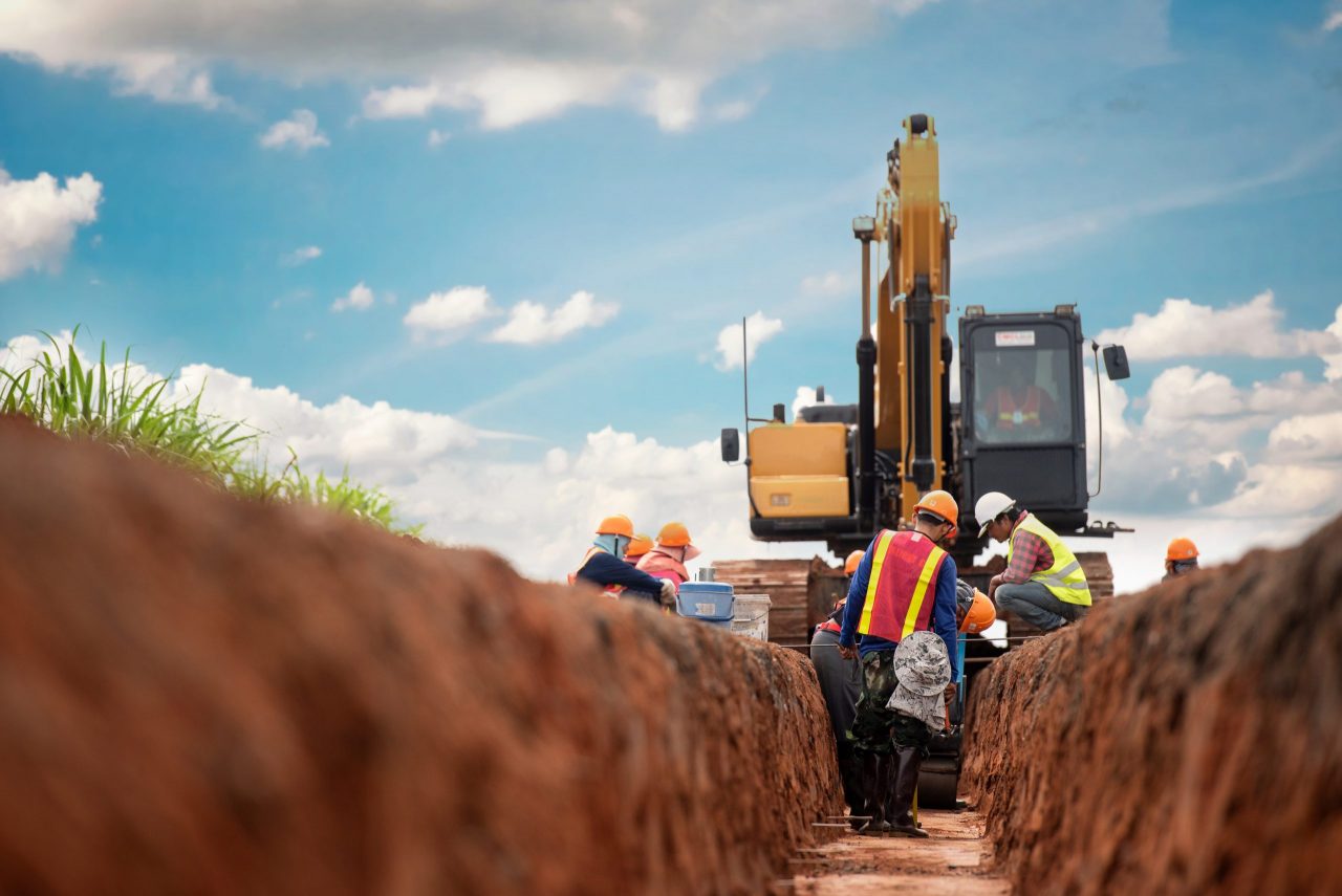 bulldozer digging a trench on a sunny day, several construction workers are present - workers' compensation attorneys in southern california